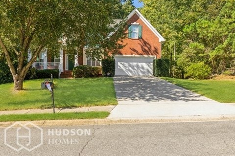 a small brick house with a driveway and a garage door