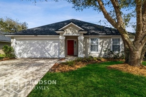 a white house with a red door and a tree