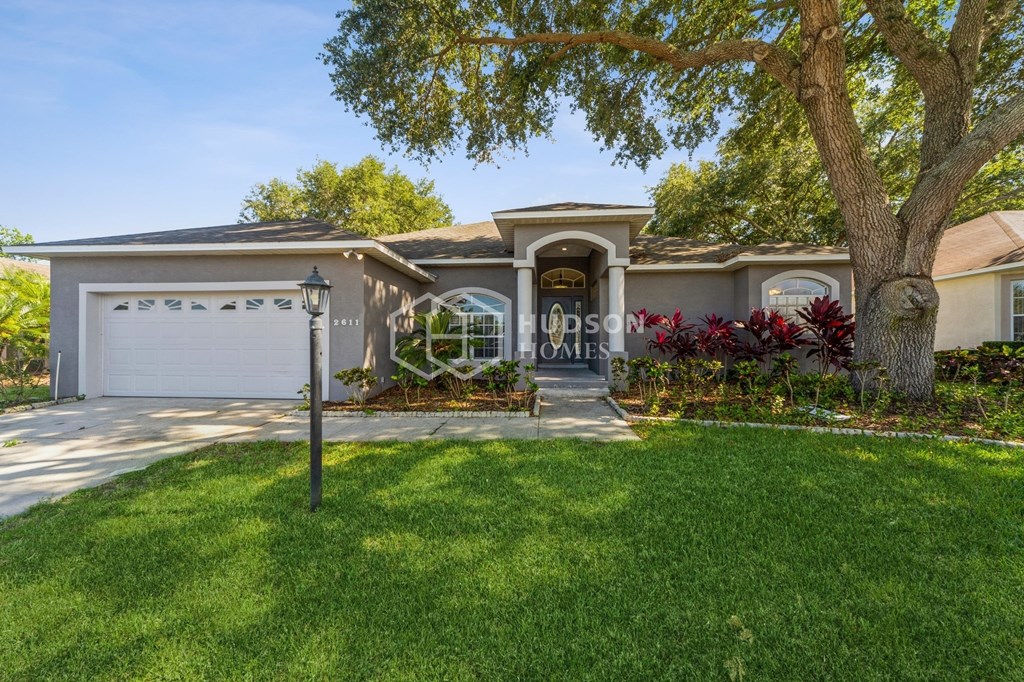 a house with a tree in the yard and a garage door