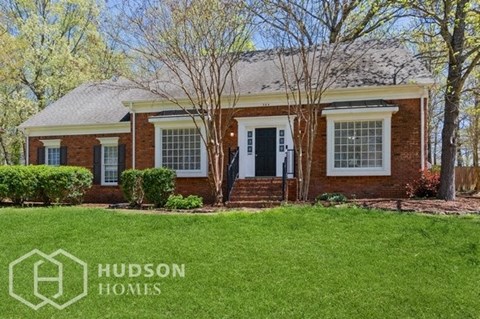 a small brick house with a lawn in front of it