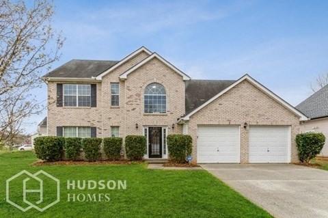 a brick house with two garage doors and a lawn