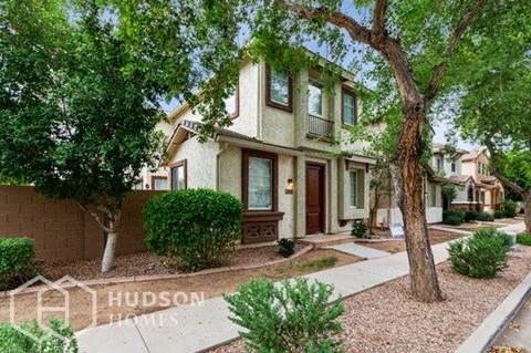 a house with trees and a sidewalk in front of it
