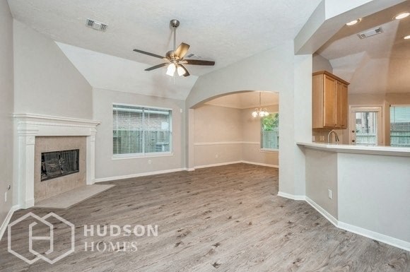 an empty living room with a fireplace and a ceiling fan