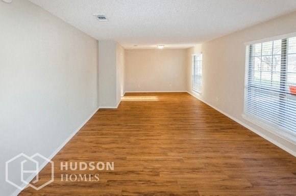 an empty living room with wood flooring and a large window