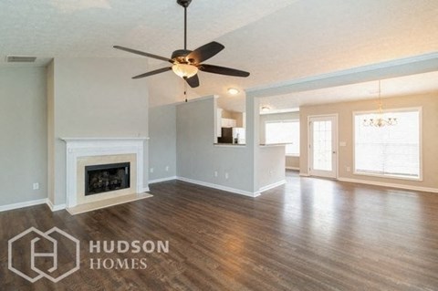 A spacious living room with a fireplace and a ceiling fan.