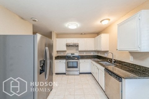 a kitchen with white cabinets and a stainless steel refrigerator