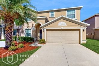 a house with a garage door and a palm tree