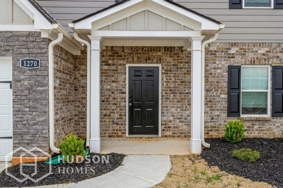 a brick house with a black door and a porch