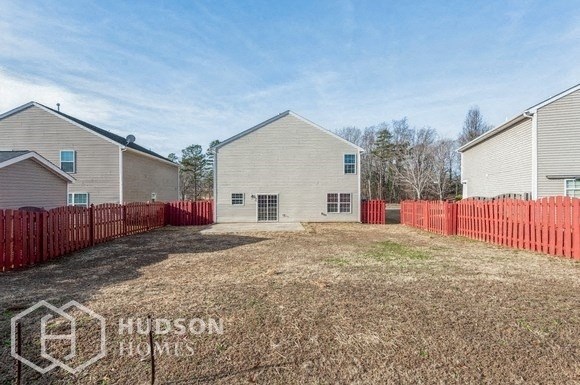 a backyard with a white house and a red fence