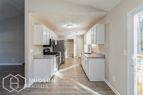 a large kitchen with white cabinets and a large window