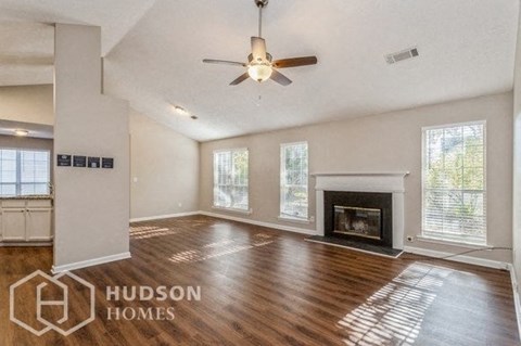 an empty living room with a ceiling fan and a fireplace