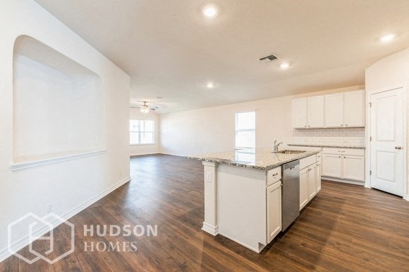 a large kitchen with white cabinets and a marble counter top