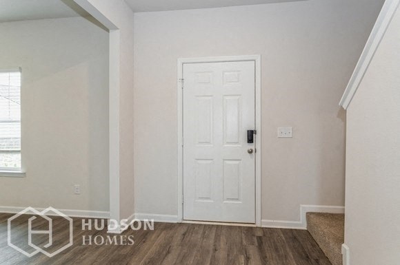 an empty room with a white door and a staircase