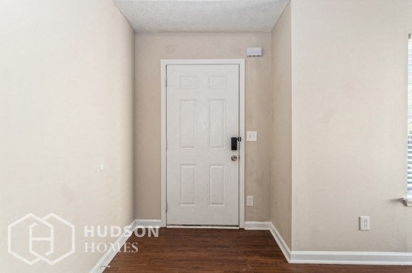 an empty room with a white door and a wooden floor