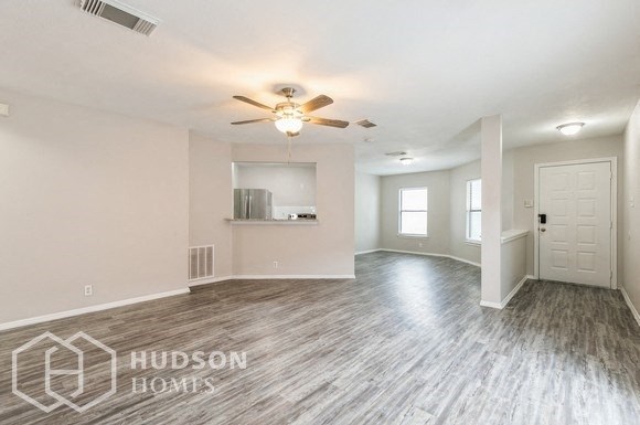 the living room and dining room with wood flooring and a ceiling fan
