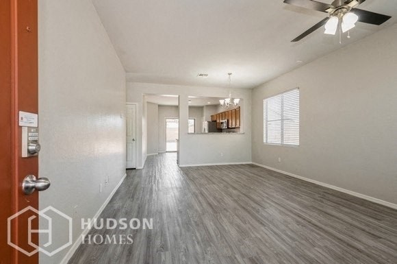 an empty living room and kitchen with a ceiling fan
