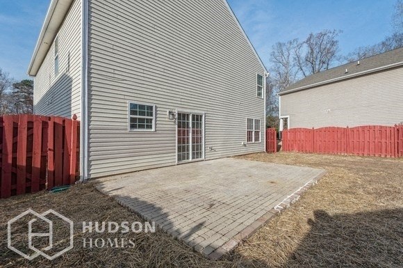 a backyard patio with a white house and a red fence