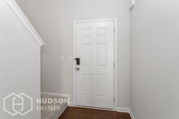 a room with a white door and a hallway with a carpet