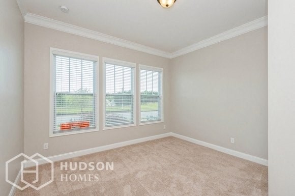 an empty living room with three windows and a carpet