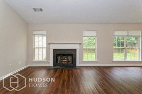an empty living room with a fireplace and wooden floors