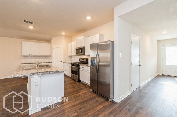 a kitchen with white cabinets and a stainless steel refrigerator