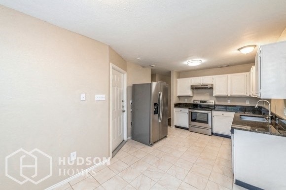 a kitchen with white cabinets and a stainless steel refrigerator