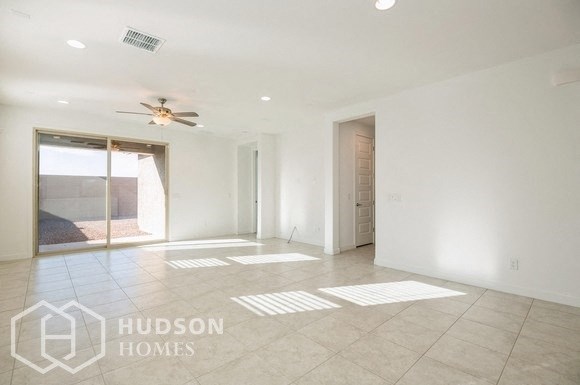 an empty living room with a ceiling fan and a door to a patio
