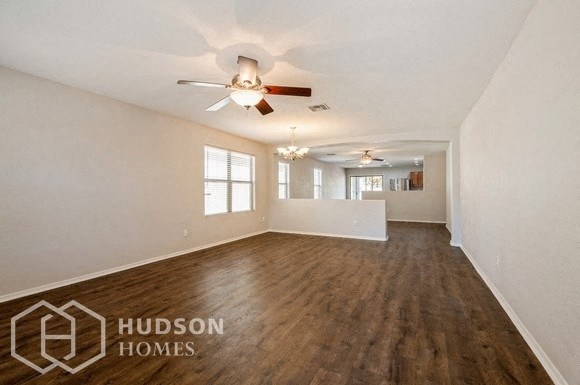 an empty living room with white walls and a ceiling fan