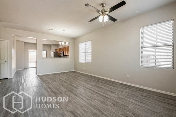 an empty living room with a ceiling fan and a kitchen