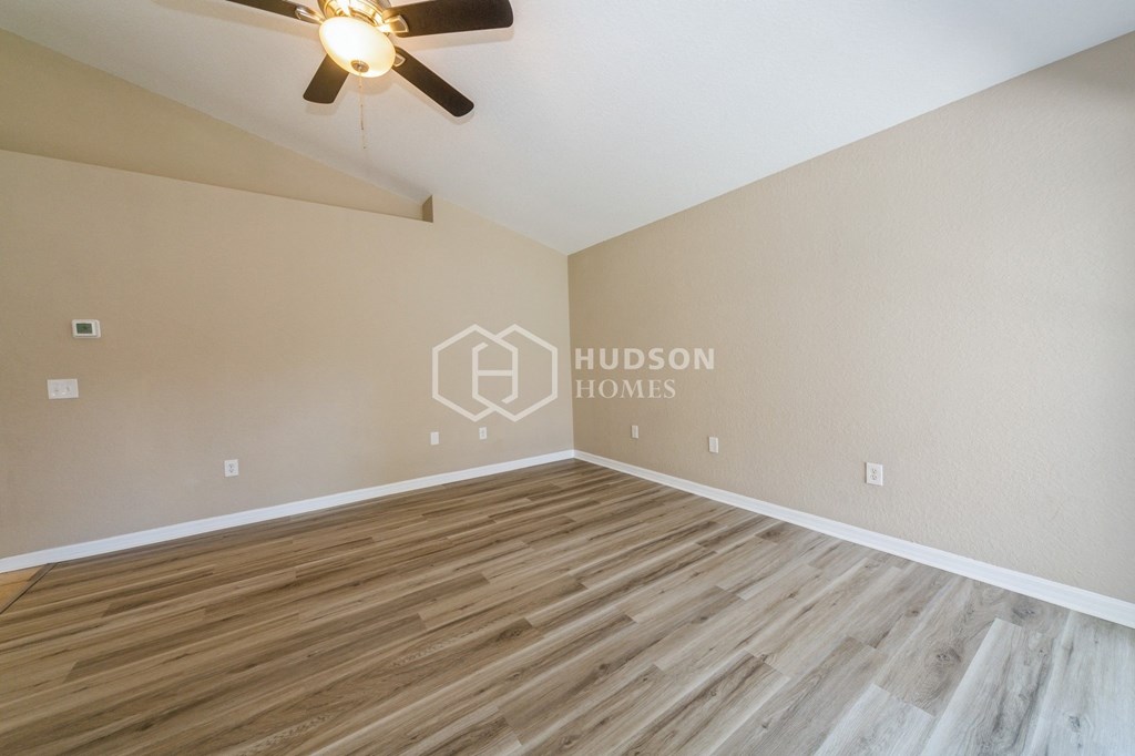 a bedroom with hardwood floors and a large empty room