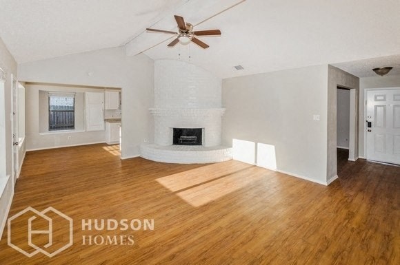an empty living room with a fireplace and a ceiling fan