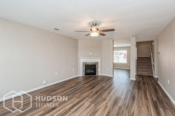 an empty living room with a ceiling fan and a fireplace