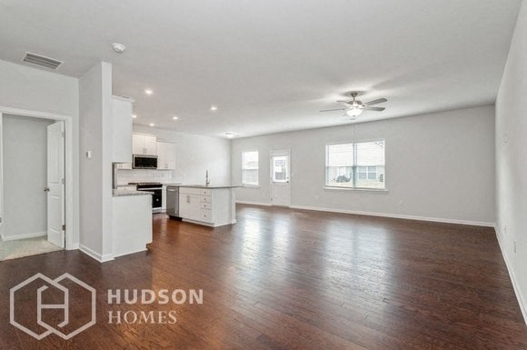 an empty living room and kitchen with a ceiling fan