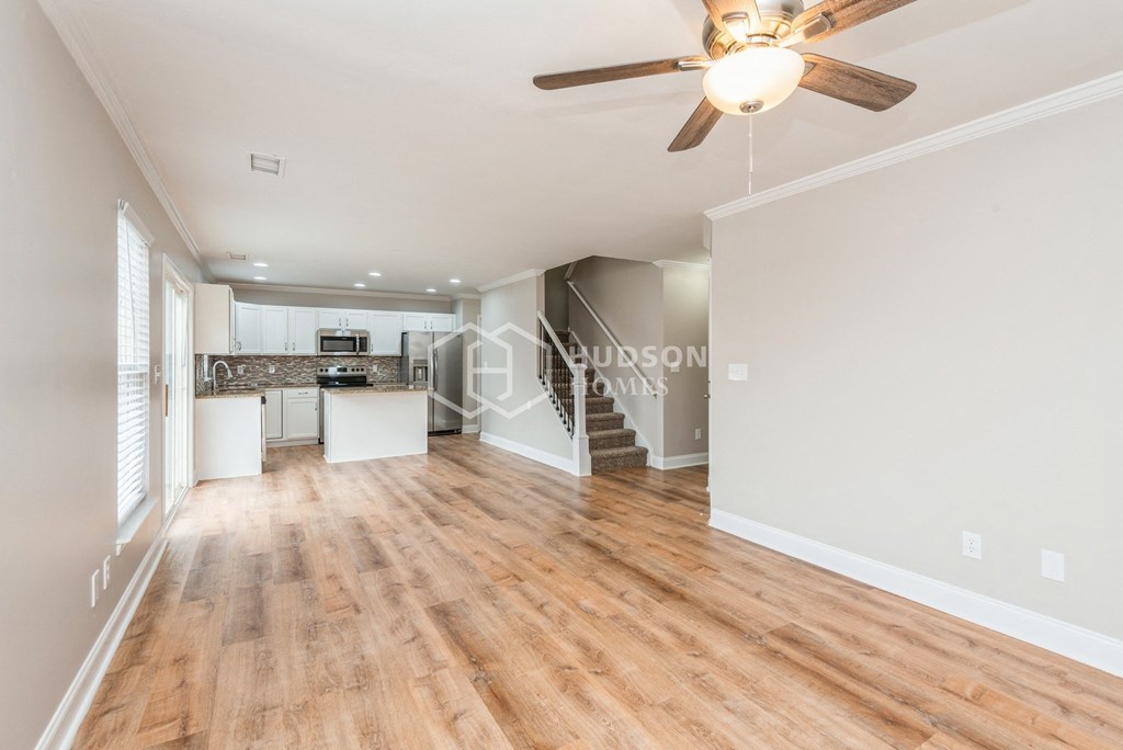 a renovated living room and kitchen with hardwood floors and a ceiling fan