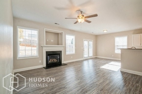 an empty living room with a fireplace and a ceiling fan