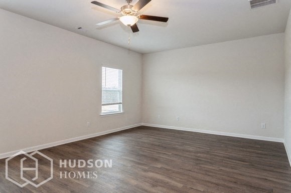 an empty living room with a ceiling fan and a window