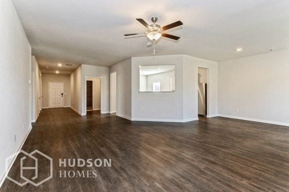 an empty living room with a ceiling fan and white walls