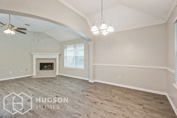 an empty living room with a fireplace and a ceiling fan