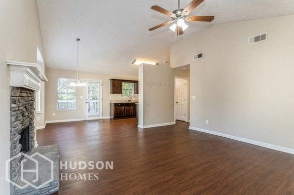 an empty living room with a fireplace and a ceiling fan
