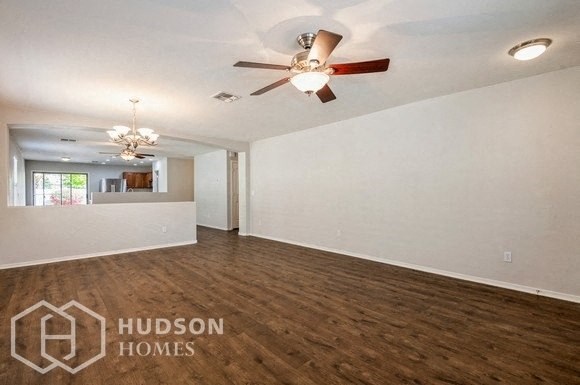an empty living room with a ceiling fan and white walls
