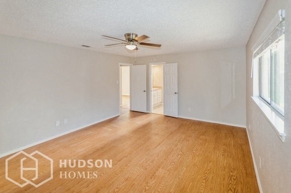 an empty living room with wood flooring and a ceiling fan