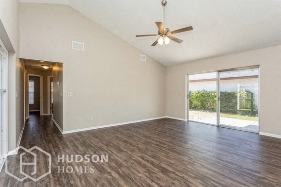 an empty living room with wood floors and a ceiling fan