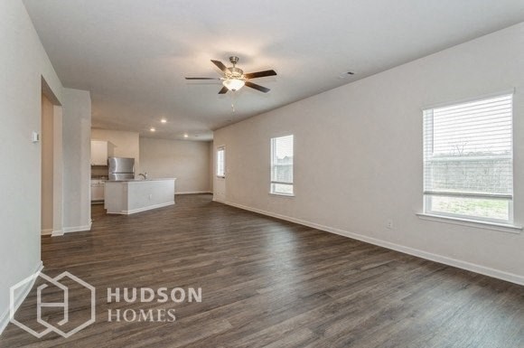 an empty living room with a ceiling fan and a kitchen
