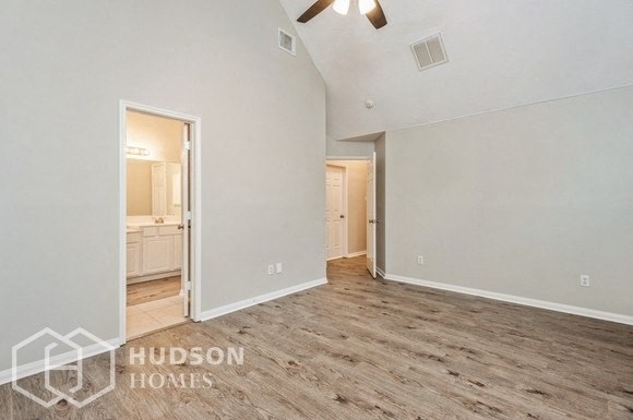 a spacious living room with wood flooring and a door to the bathroom