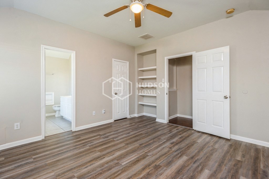 an empty living room with a ceiling fan and a closet