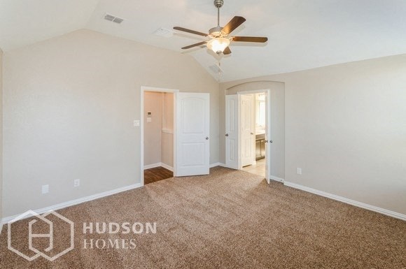 an empty living room with a ceiling fan and a carpet