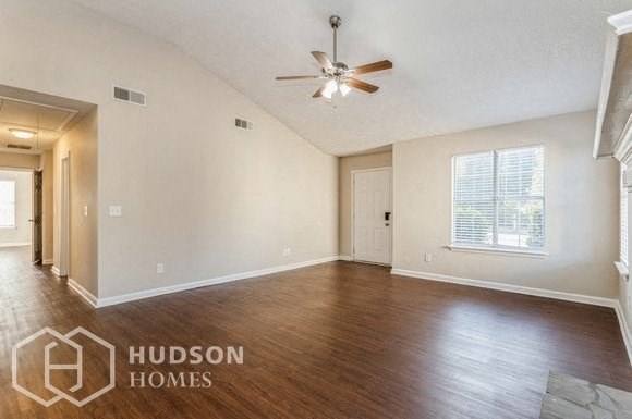 an empty living room with wood floors and a ceiling fan