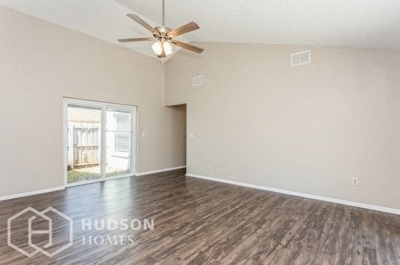 an empty living room with a ceiling fan and a window