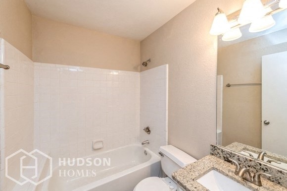 a white bathroom with a tub and a sink and a mirror