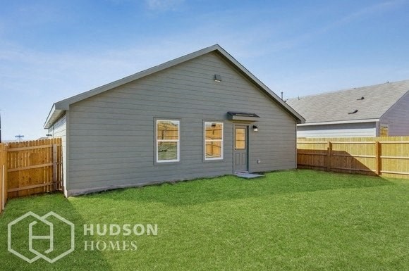 a small gray house with a yard and a fence